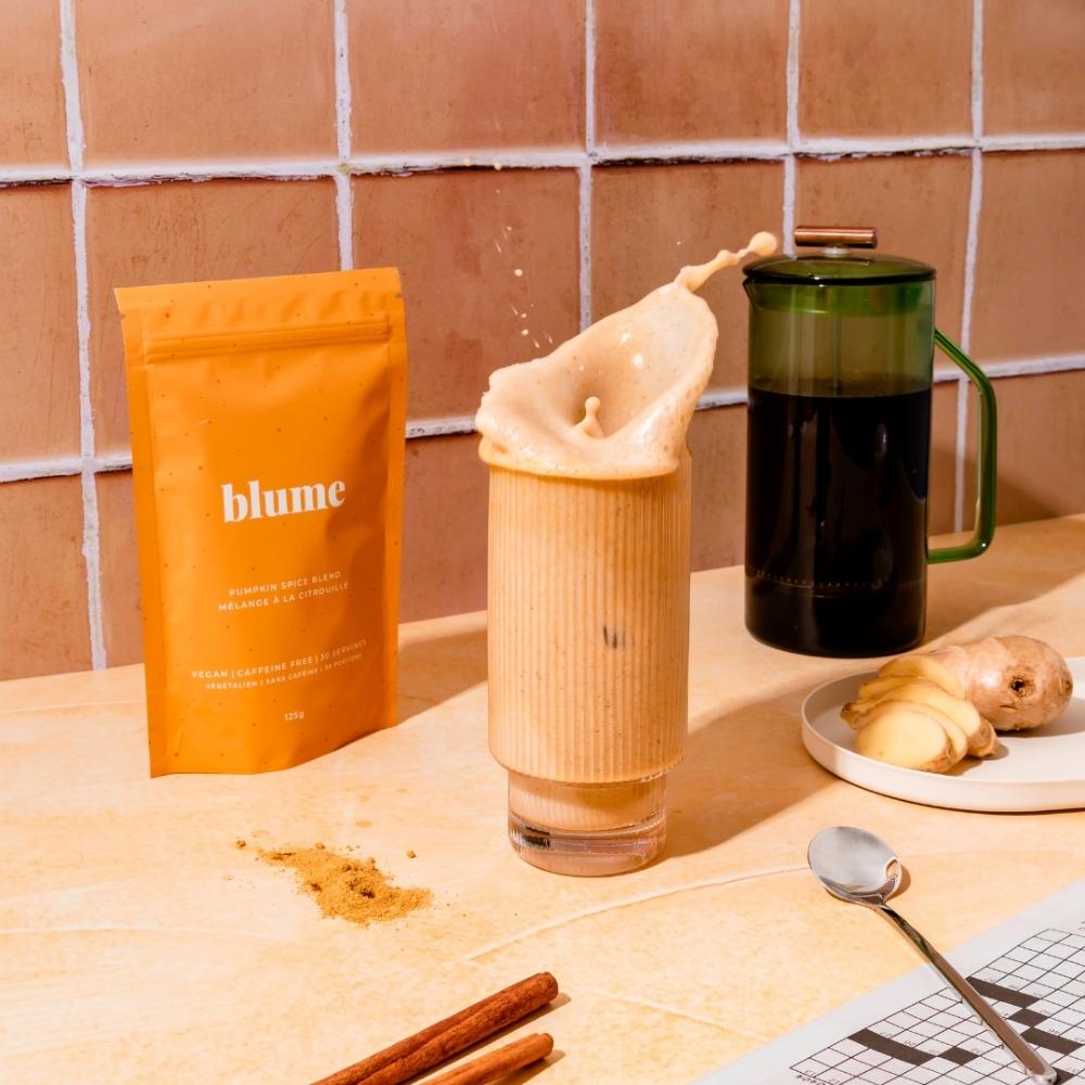 Blume pumpkin spice latte splash, next to French press, ginger, and cinnamon sticks.